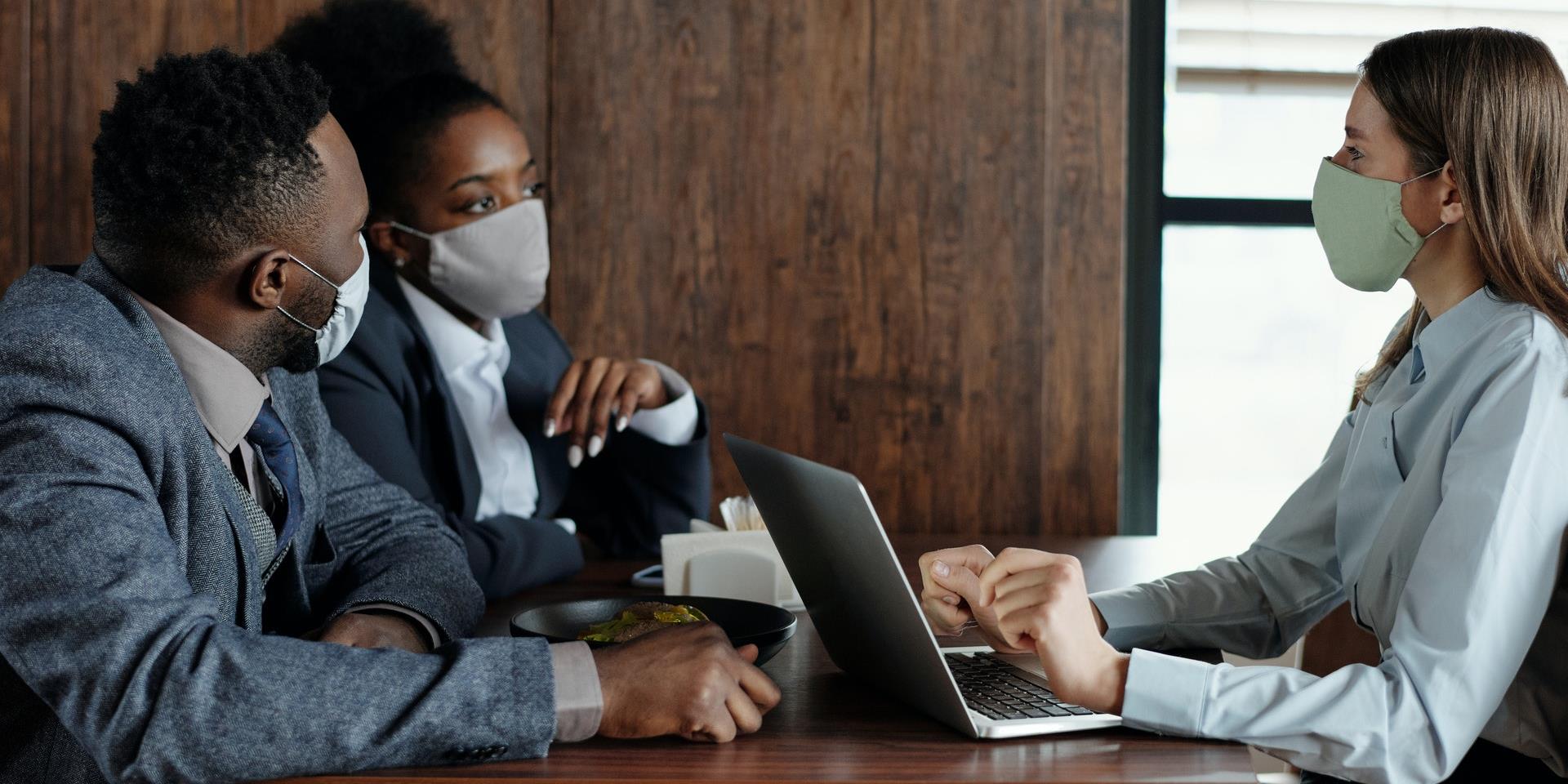 Three people in masks and business attire