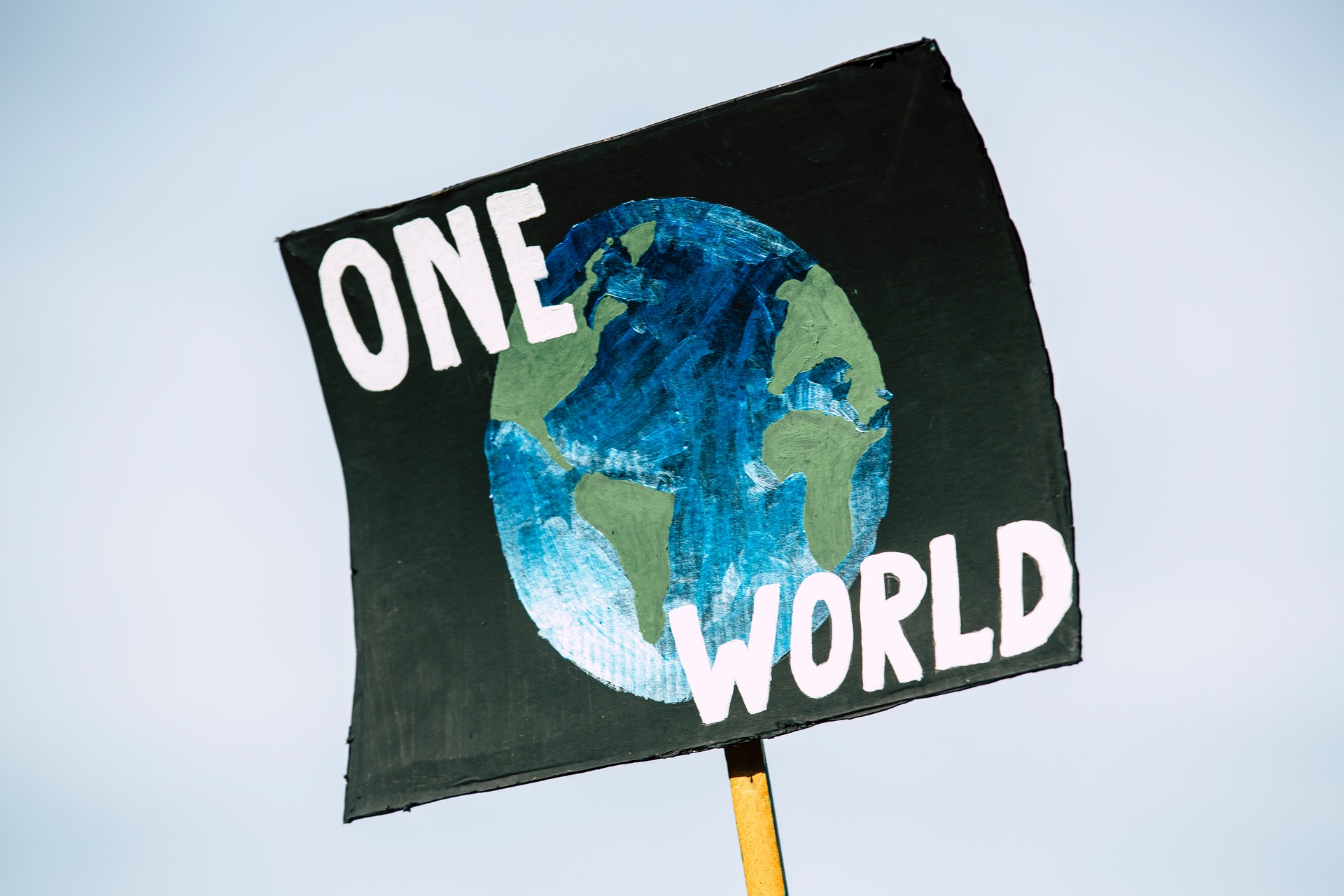 Zdjęcie plakatu z namalowaną planetą i napisem "jeden świat" po angielsku