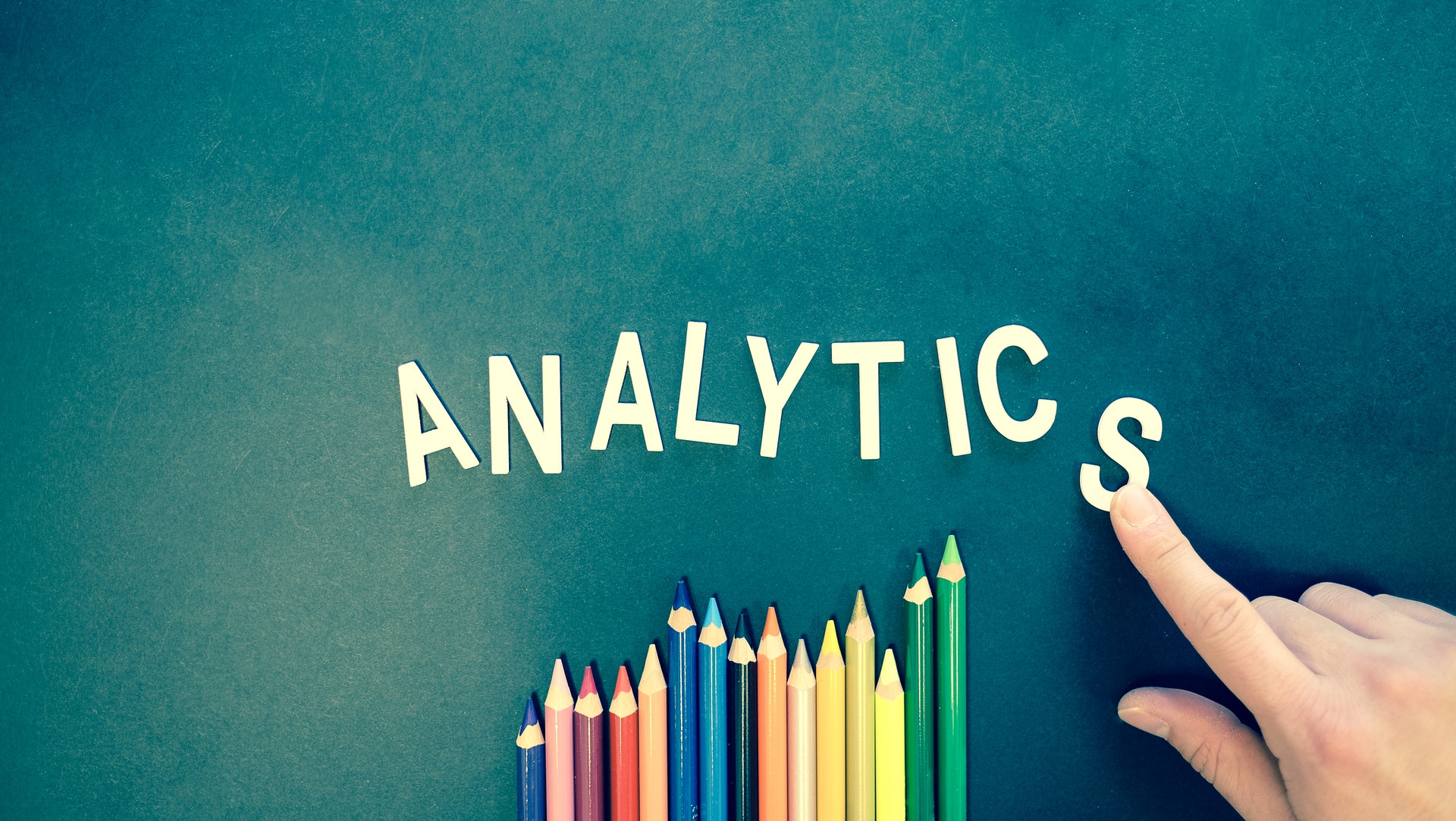 Zdjęcie wykresu z kredek i liter ułożonych w napis "analytics"